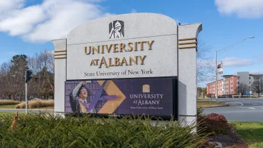 State University of New York at Albany campus sign with a blue sky in the background