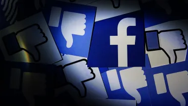 Close up Facebook logo surrounded by thumbs down icons. (Image via Shutterstock.com)