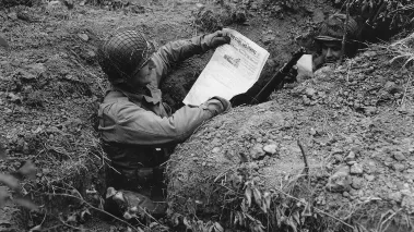 soldier in foxhole reading paper