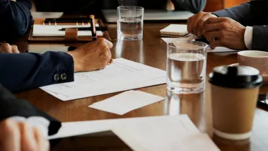 hands of people using phones and writing during a board meeting