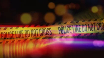 Yellow Tape Showing Text "Police Line Do Not Cross" with police flashers in background