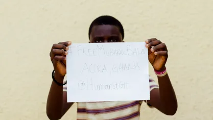 Protesters holds up a piece of paper with Mubarak Bala's name