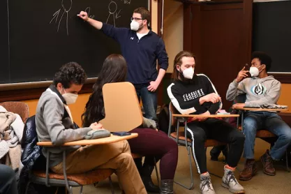 Student writing on chalkboard at John Stuart Mill Forum at Wooster College.