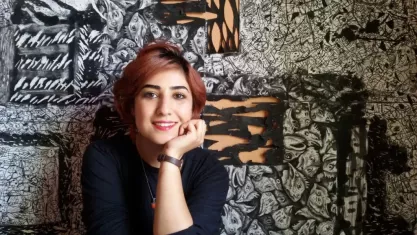 Atena Farghadani sitting for a photograph in front of a painting.