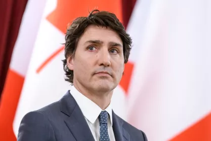 Canadian Prime Minister Justin Trudeau standing before a row of Canadian flags