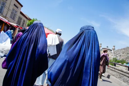 Two women in blue burqas walk on a street in Kabul Afghanistan