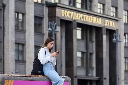 Girl sitting with a smartphone on the bench against the State Duma in Moscow