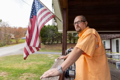 FIRE client Joshua Gibbons outside his home in Tennessee, next to the American flag.