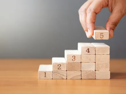 Hand building steps out of toy wood blocks