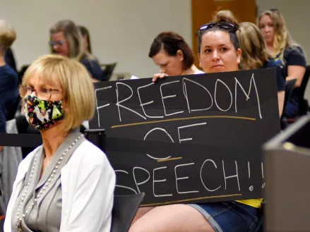 Woman holds a sign reading "freedom of speech" during a Brevard County School Board meeting 
