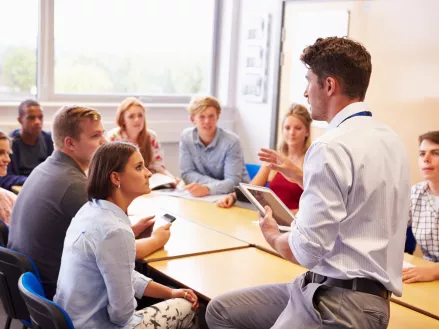 Teacher With College Students Giving Lesson In Classroom
