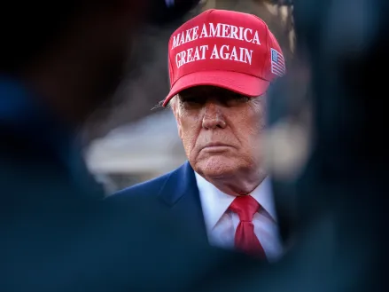 Donald Trump speaks to reporters wearing red MAGA hat