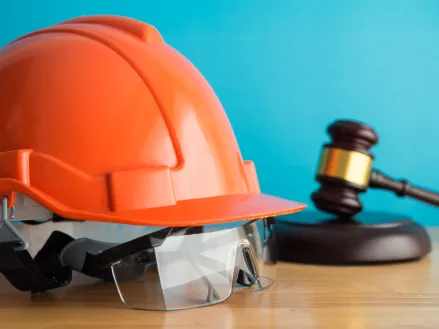 Construction helmet and worker safety glasses on table indicating legal protection