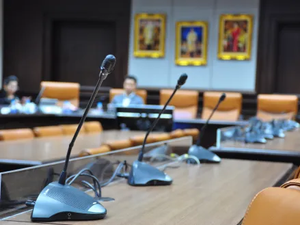 Microphones on a table for a school board meeting (Image via Shutterstock.com)