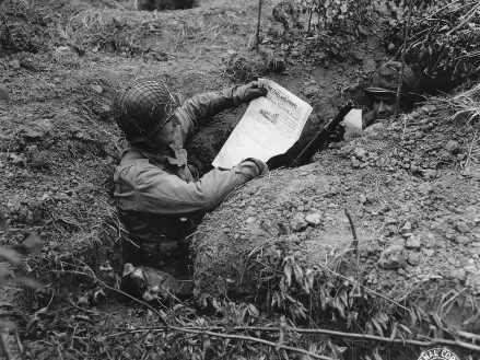 soldier in foxhole reading paper