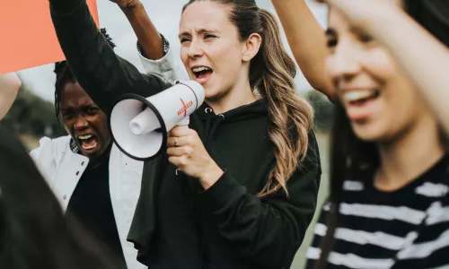 Peaceful protest with young woman speaking into a megaphone.