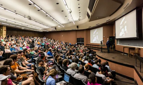 Professor Neil Shubin delivers a lecture to a large audience of college students at the University of Texas at Austin.