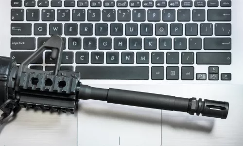 Photo of the barrel of a rifle on top of a keyboard