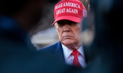 Donald Trump speaks to reporters wearing red MAGA hat