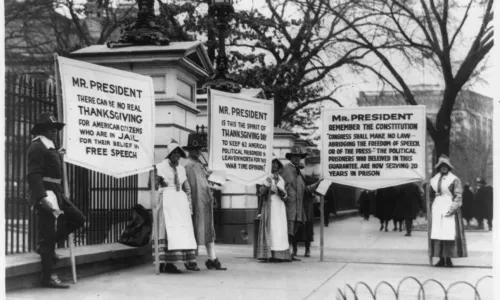 Protesters dressed as pilgrims carry signs calling for amnesty for political prisoners standing in front of the White House, circa 1918.