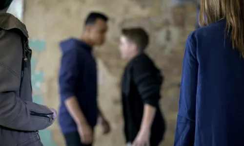 Teenage boys fighting true threats with blurred background (Image via Shutterstock.com)