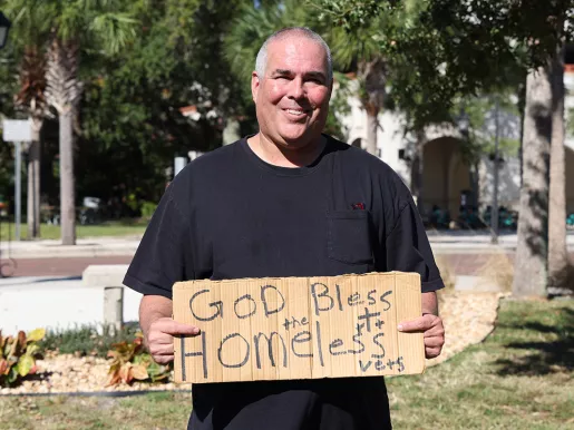 FIRE plaintiff Jeff Gray holds a sign reading "God bless homeless vets"