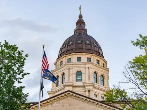 Dome of the Kansas State Capital Building in Topeka with the state flag in the foreground