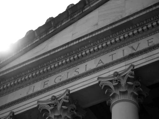 Black and white exterior of Legislative chambers of the Washington State Capitol in Olympia with inscription and pillars