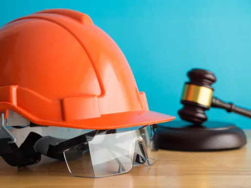 Construction helmet and worker safety glasses on table indicating legal protection