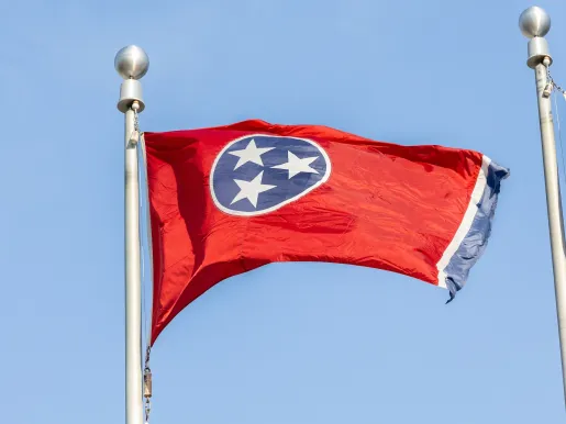 Tennessee state flag blowing in the wind with a blue sky background. (Image via Shutterstock.com)