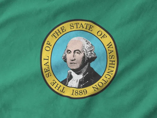 Washington state flag depicted on folded wavy fabric of old cloth close up (Image via Shutterstock.com)