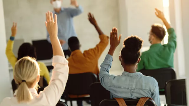 Students raising hands in class showing academic freedom rights