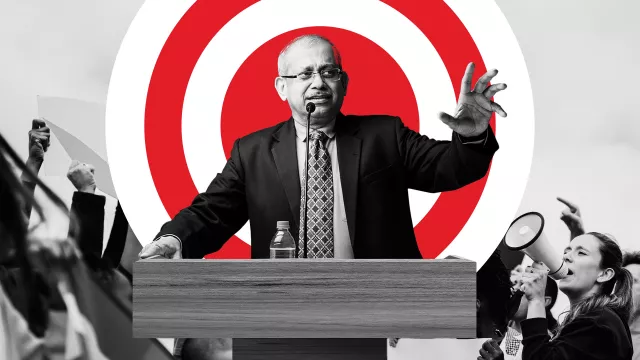 Man at a podium standing in front of a red bullseye 