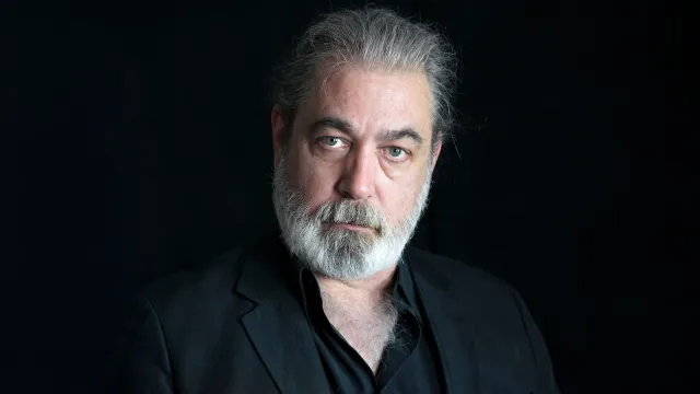 Photo of CJ Hopkins in a black shirt before a black background.