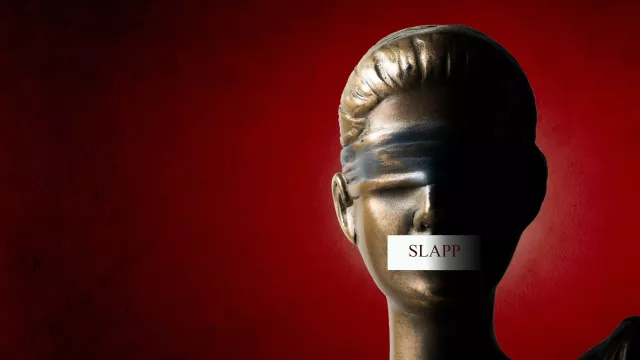 Statue of justice with tape over the mouth and written on the tape is the word "SLAPP" meaning "Strategic Lawsuit against Public Participation"