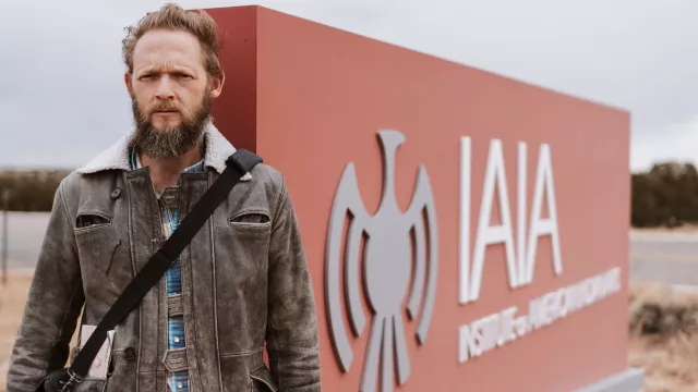 David McNicholas in front of a sign for the Institute of American Indian Arts