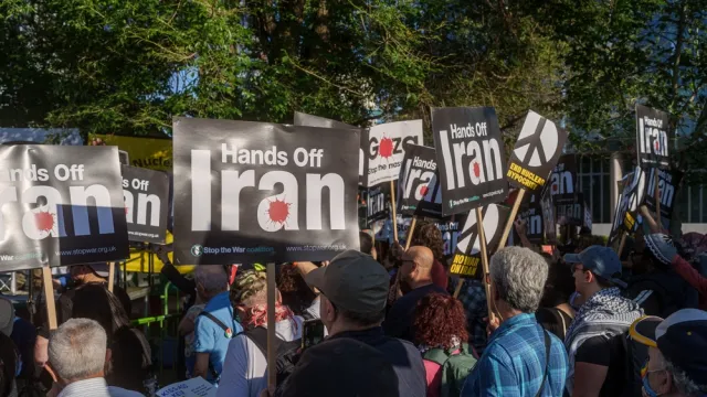 Protesters gather with Palestinian flags and "Hands Off Iran" signs during a demonstration near the US Embassy in London.