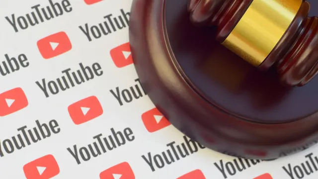 Youtube paper logo lies with wooden judge gavel. (Image via Shutterstock.com)