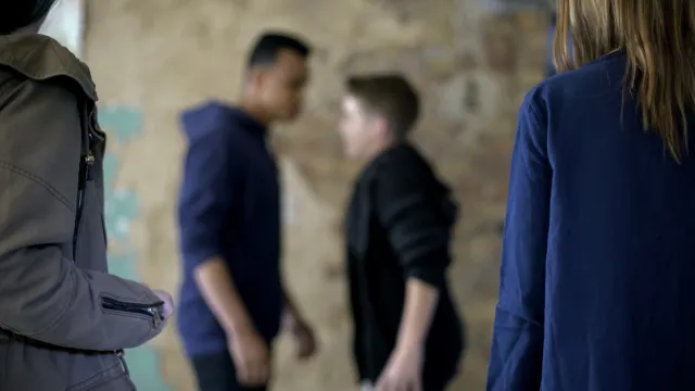 Teenage boys fighting true threats with blurred background (Image via Shutterstock.com)