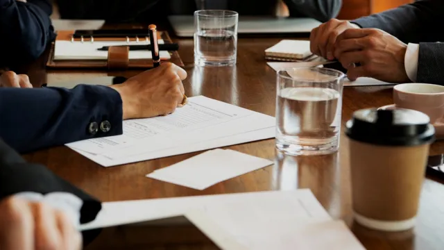 hands of people using phones and writing during a board meeting