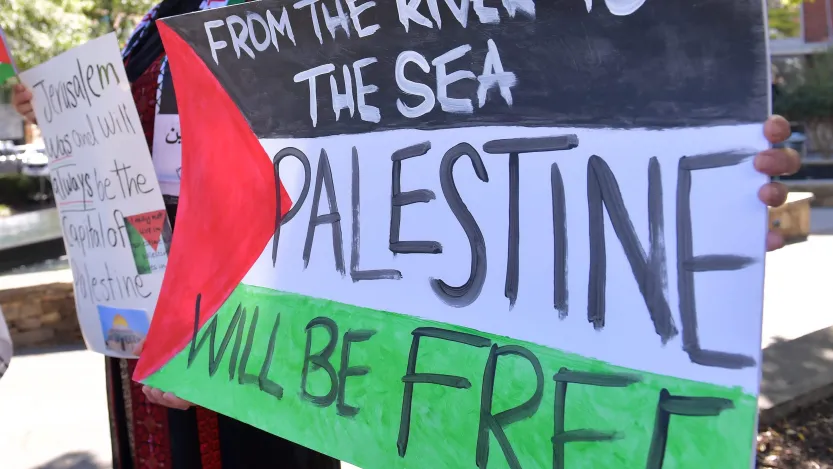 Protestor holding a sign that reads "From the River to the Sea, Palestine will be free" (Image via Shutterstock.com)